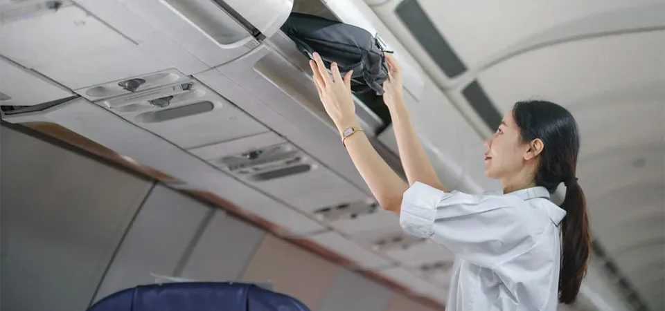 Traveller placing a carry-on bag in the overhead bin on an Ethiopian Airlines flight