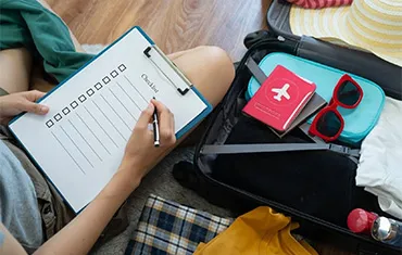 Traveller writing an air travel checklist next to packed suitcase